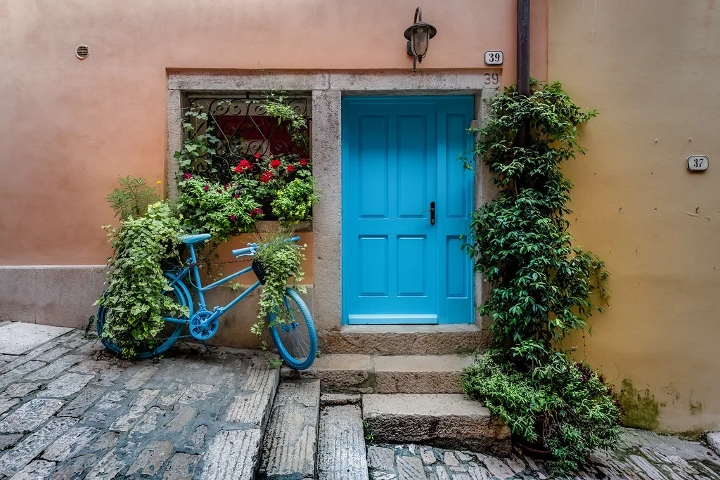 A blue door, flowers and a bicycle at a house entrance in Rovinj