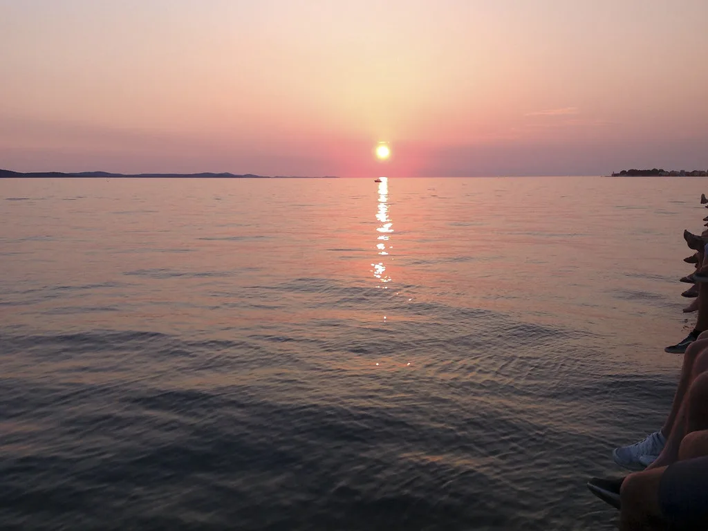 The sun setting over the sea from the Zadar waterfront by the Sea Organ