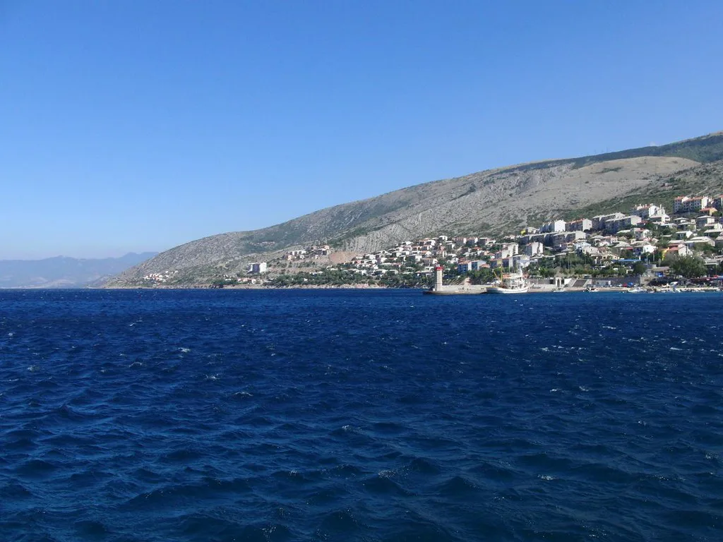 The town of Senj on the coast below bare hills, seen from the sea.