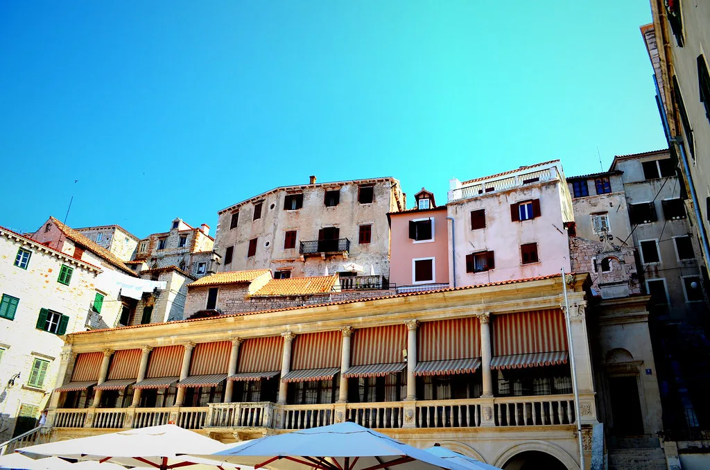 Tall old buildings above a café terrace in the old town of Šibenik