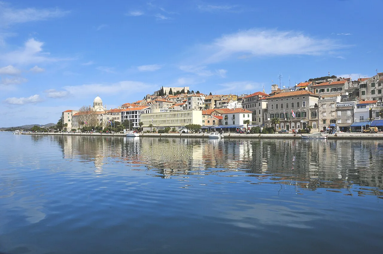 The northern shoreline of Šibenik's old town reflected in calm water, Šibenik
