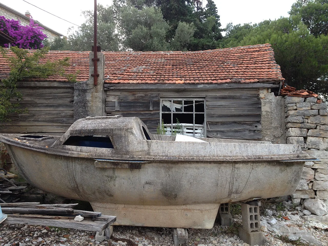 An old wooden boat beside a stone shed on Šolta.