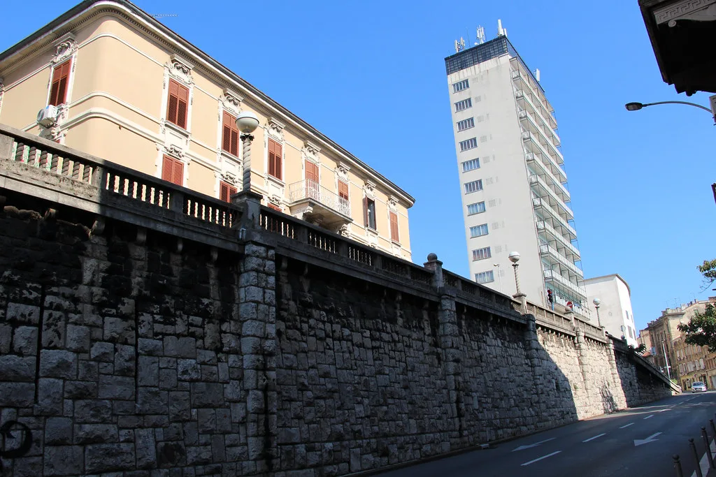 A glass high-rise and older buildings above a stone wall in Sušak, Rijeka