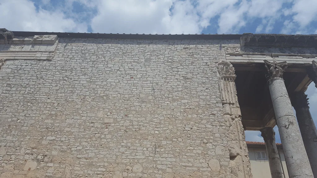 The stone side wall and front columns of the Temple of Augustus in Pula