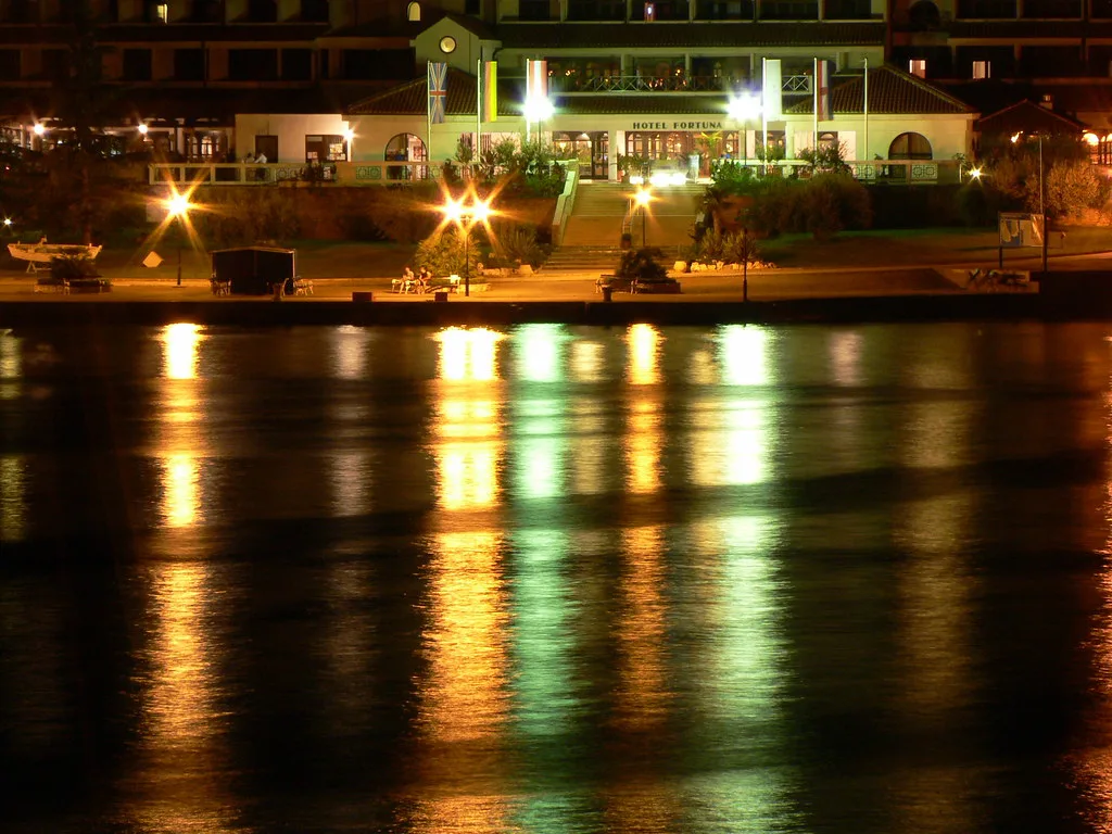 Lights along the Poreč waterfront reflected in the bay at night.