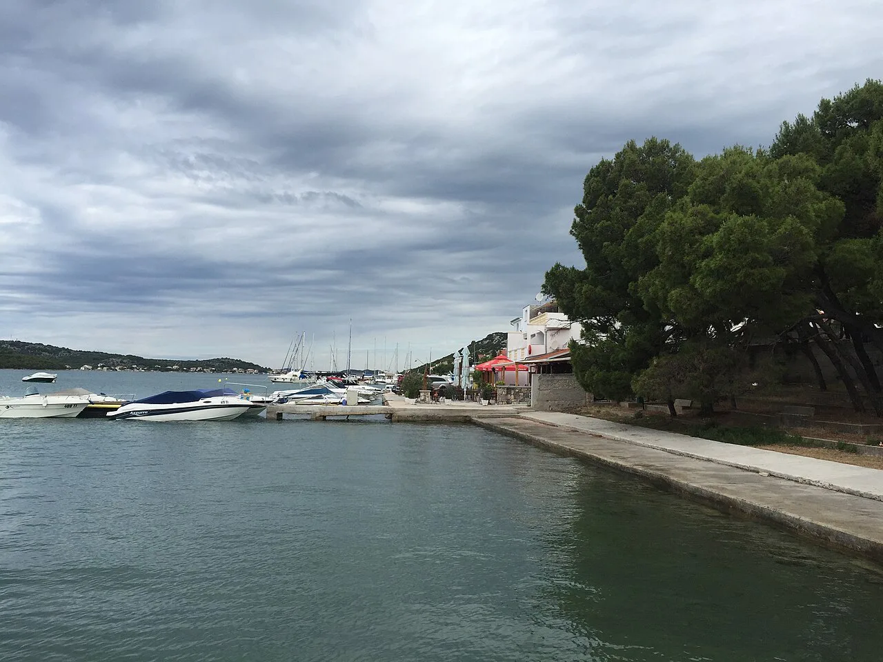 A waterfront promenade with moored boats in Tisno, Šibenik