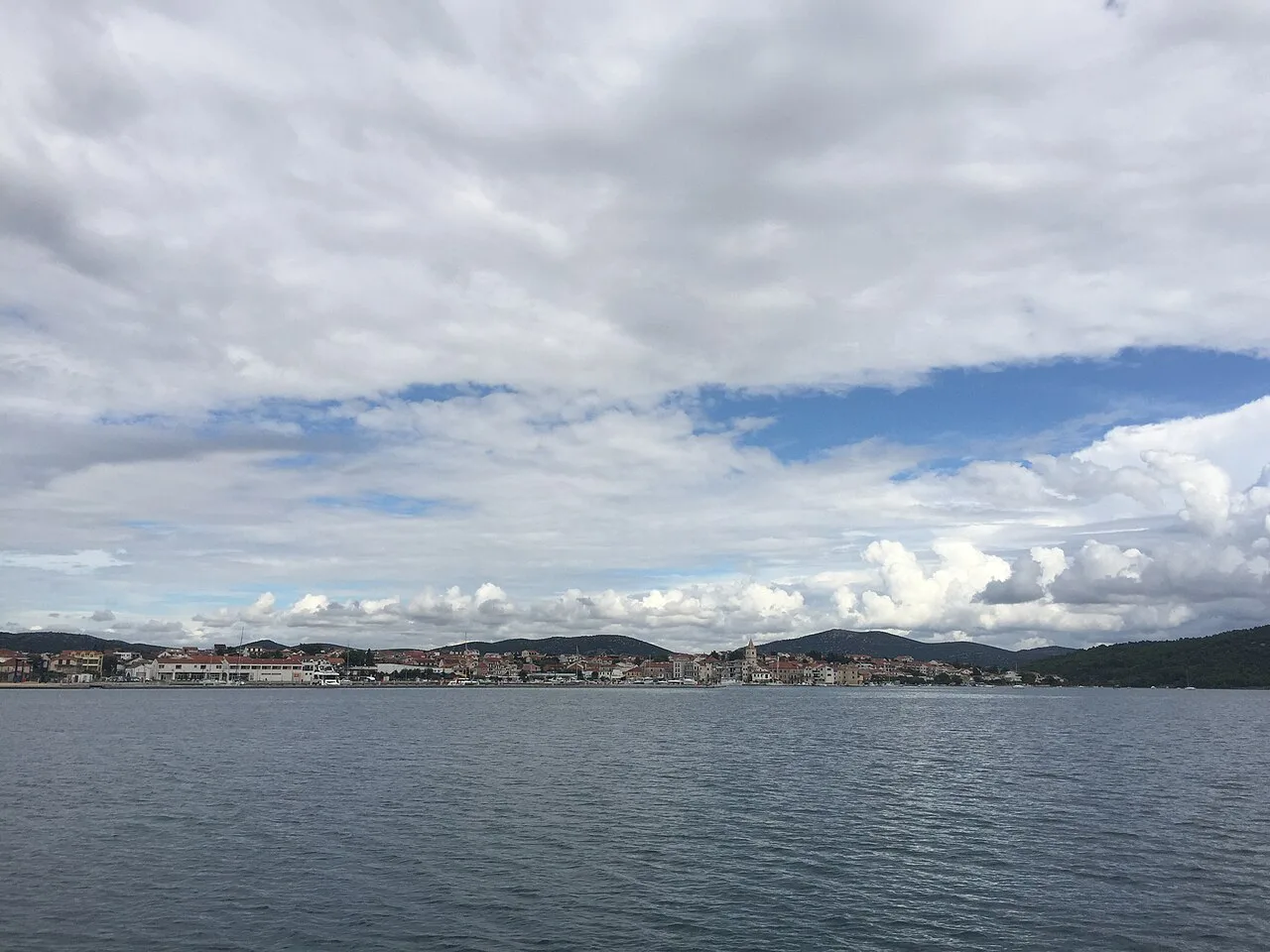 A distant view of Tisno across the calm water of the bay, Šibenik