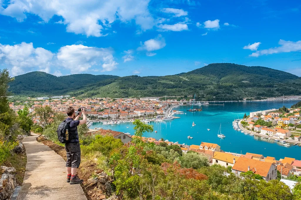A walker on a hillside path above the town and harbour of Vela Luka, Korčula