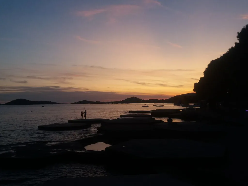Figures silhouetted on the rocks at Pod Puntom in Vodice at sunset, Dalmatia